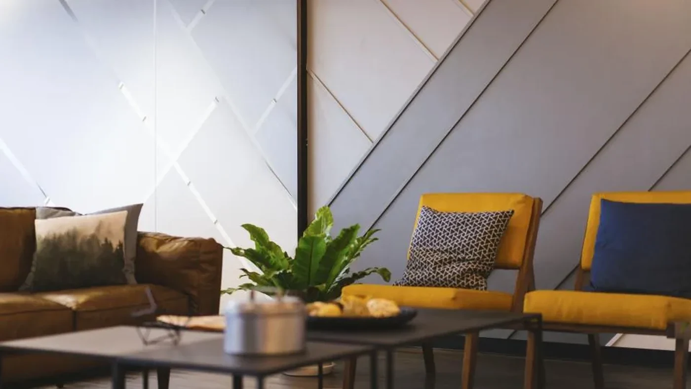 Living room with paneled wall, yellow chairs and a coffee table